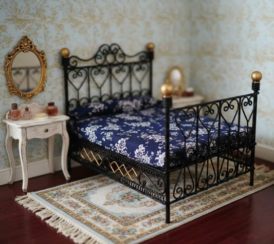 Miniature bedroom setup with a black iron bed, blue floral bedding, and decorative mirror.