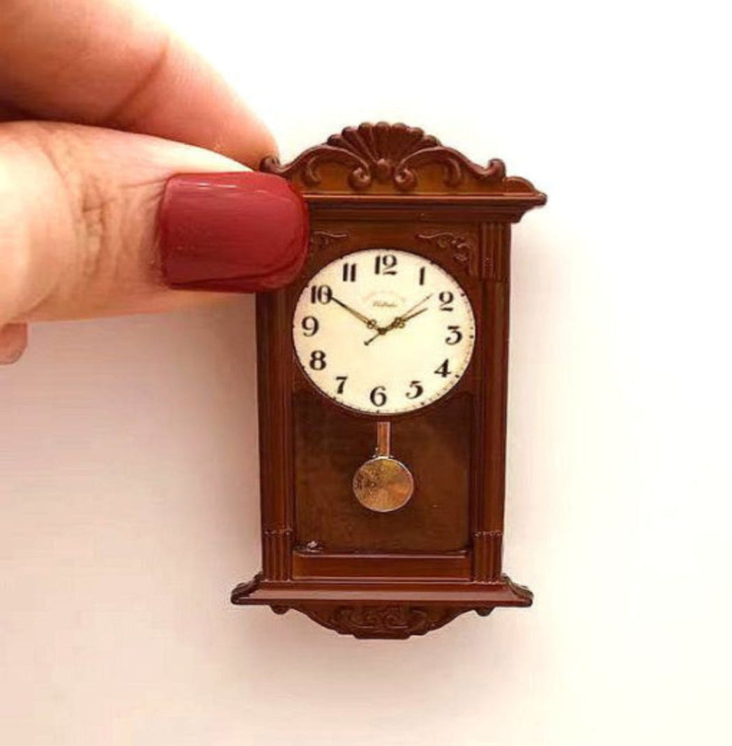 Small wooden clock held by a hand with red nail polish on a light background
