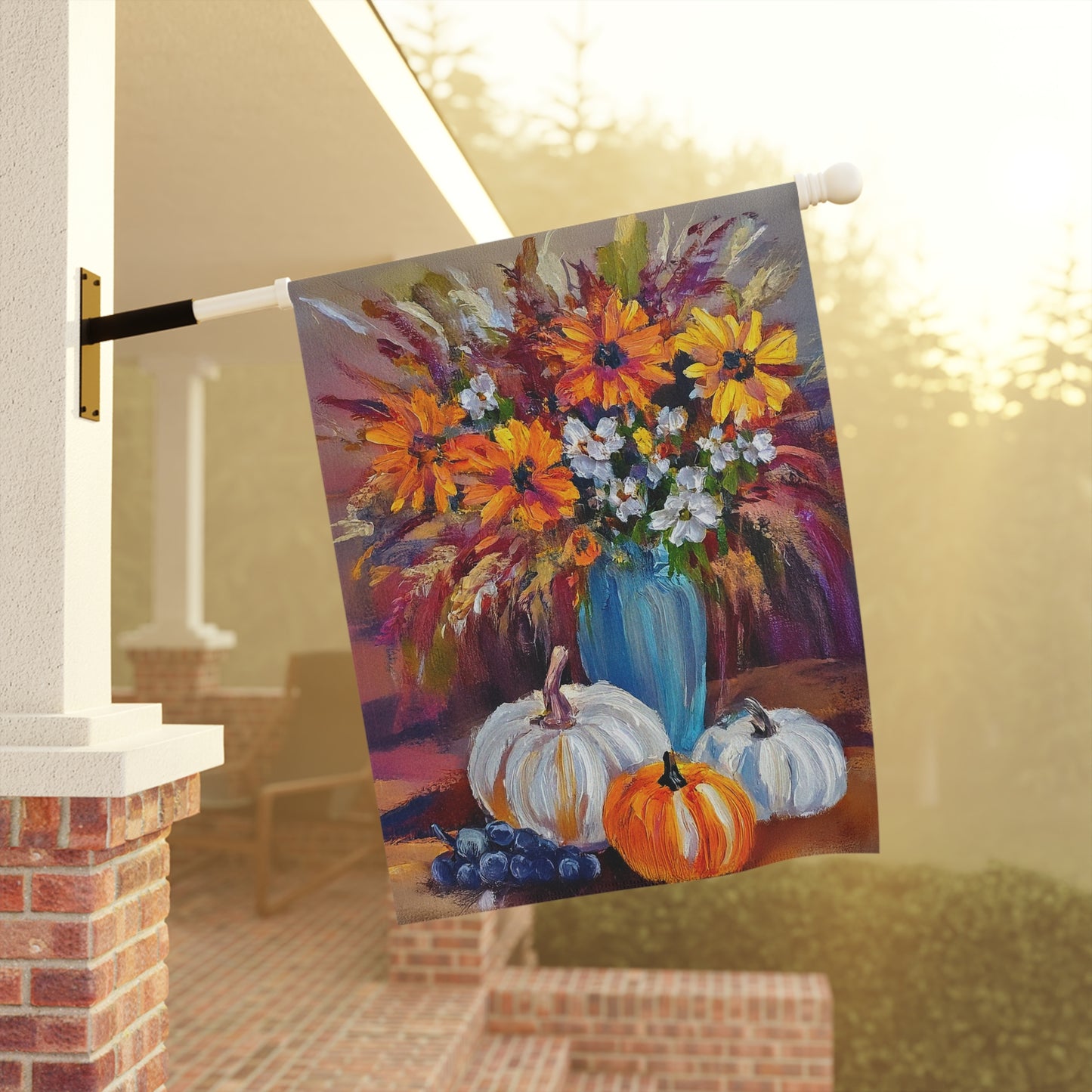 Decorative flag with a colorful floral arrangement and pumpkins hanging on a porch.