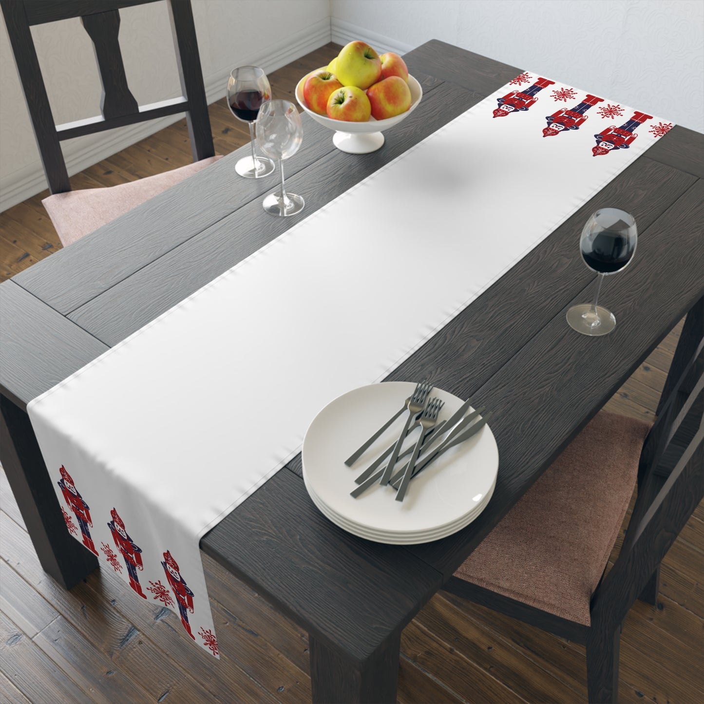 Dining table with a decorative table runner, plates, and glasses on a wooden floor. Christmas decor