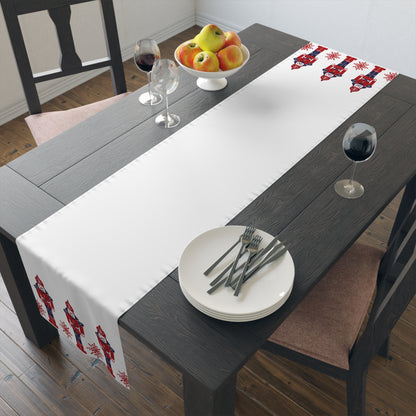 Dining table with a decorative table runner, plates, and glasses on a wooden floor. Christmas decor