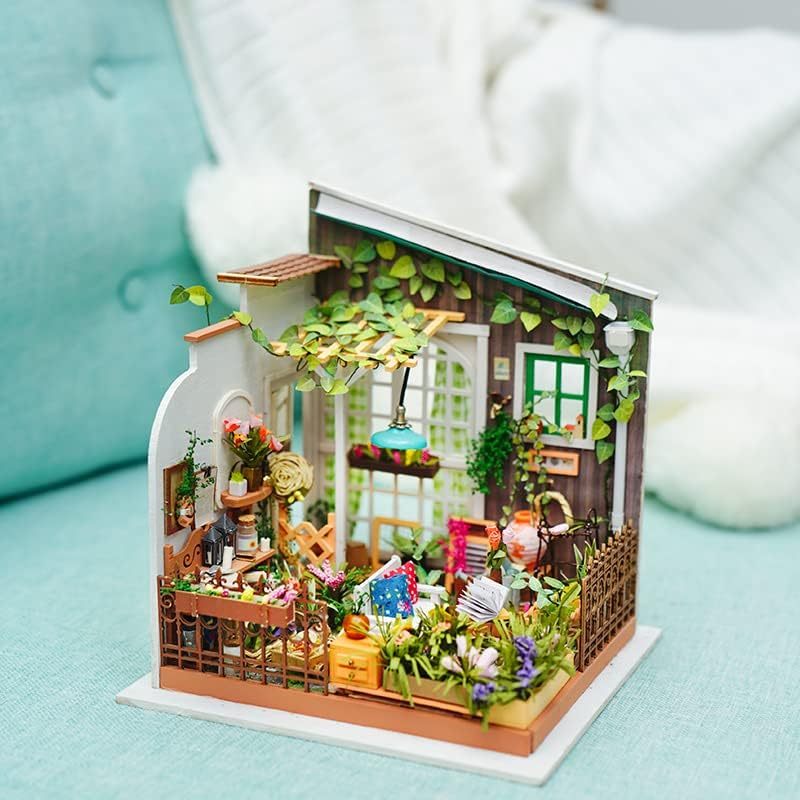 Miniature model of a cozy garden house with plants and furniture on a light blue surface. 1.24 scale miniature size
