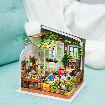 Miniature model of a cozy garden house with plants and furniture on a light blue surface. 1.24 scale miniature size