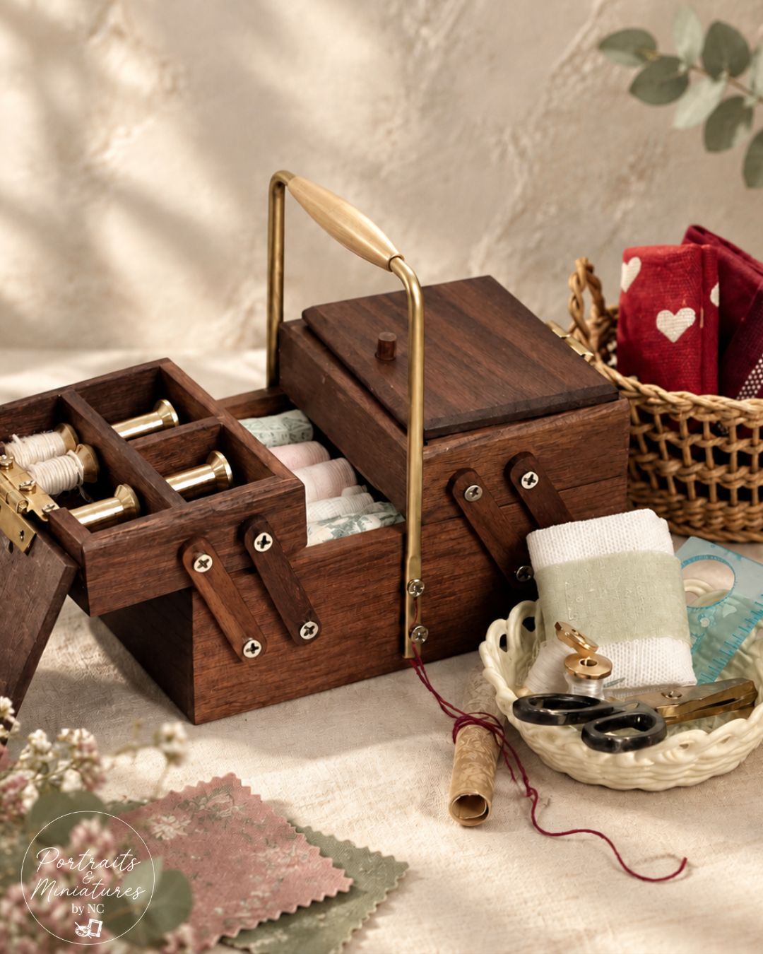 A 1/6 scale dollhouse dark brown wooden sewing box with brass hardware and a light wood handle, shown open with thread spools and sewing accessories arranged around it on a textured beige surface.