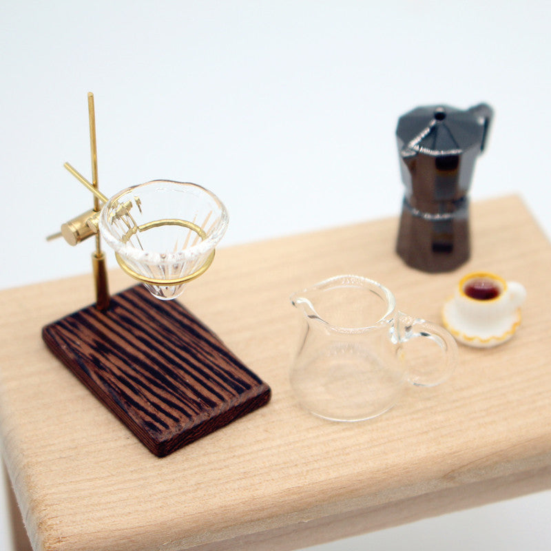 Miniature 1/12 Scale Dollhouse coffee-making setup with glass pot, coffee cup, and coffee maker on a wooden surface.