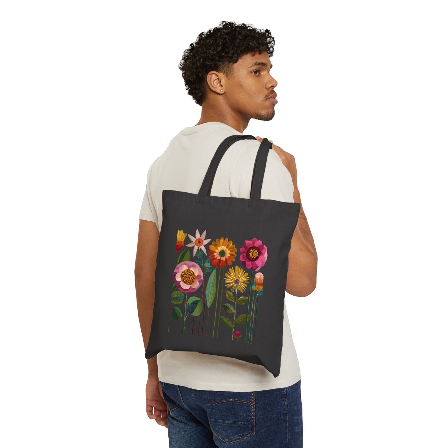 Person wearing a black tote bag with colorful floral design on a white background