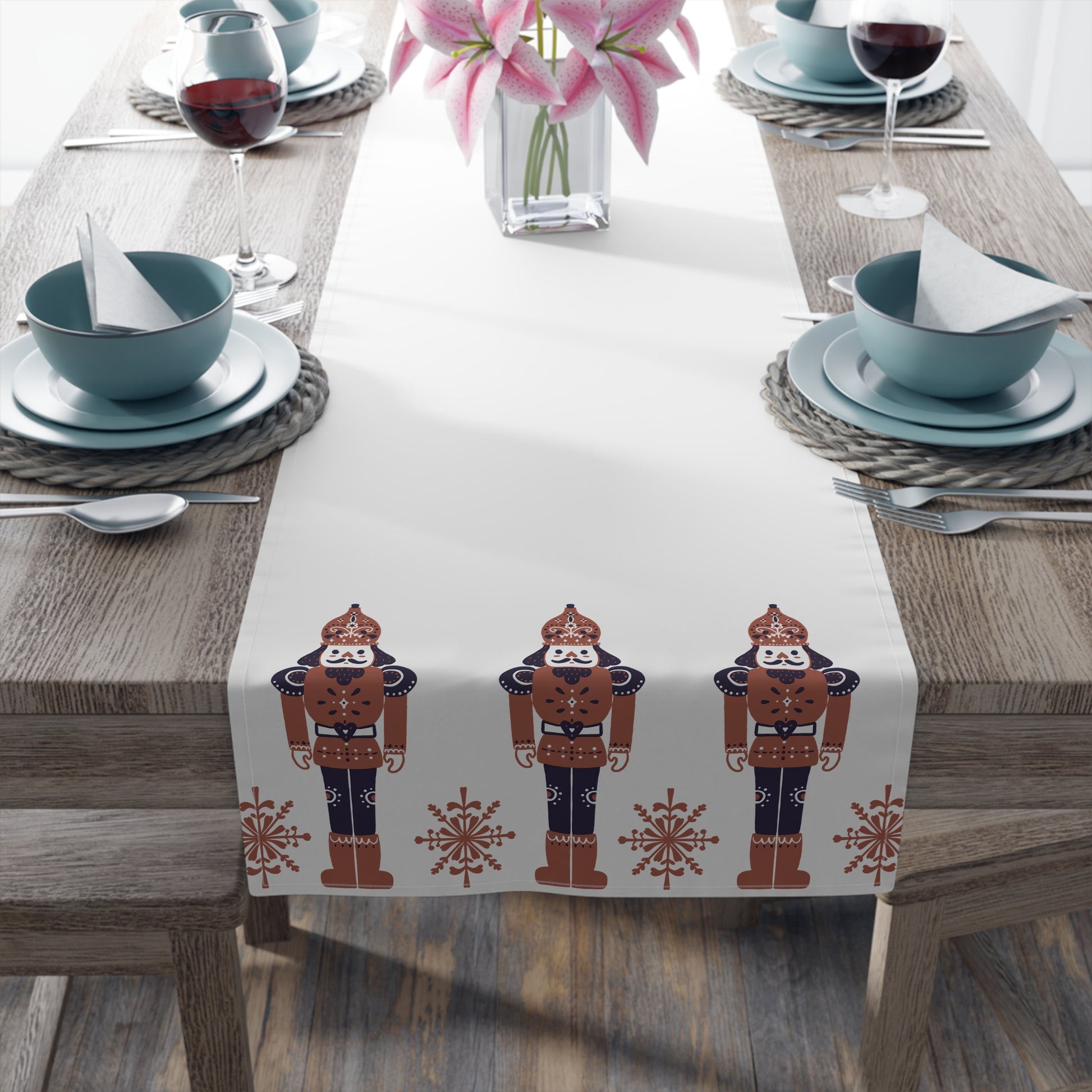 Table setting with a decorative table runner featuring nutcracker designs on a wooden table.