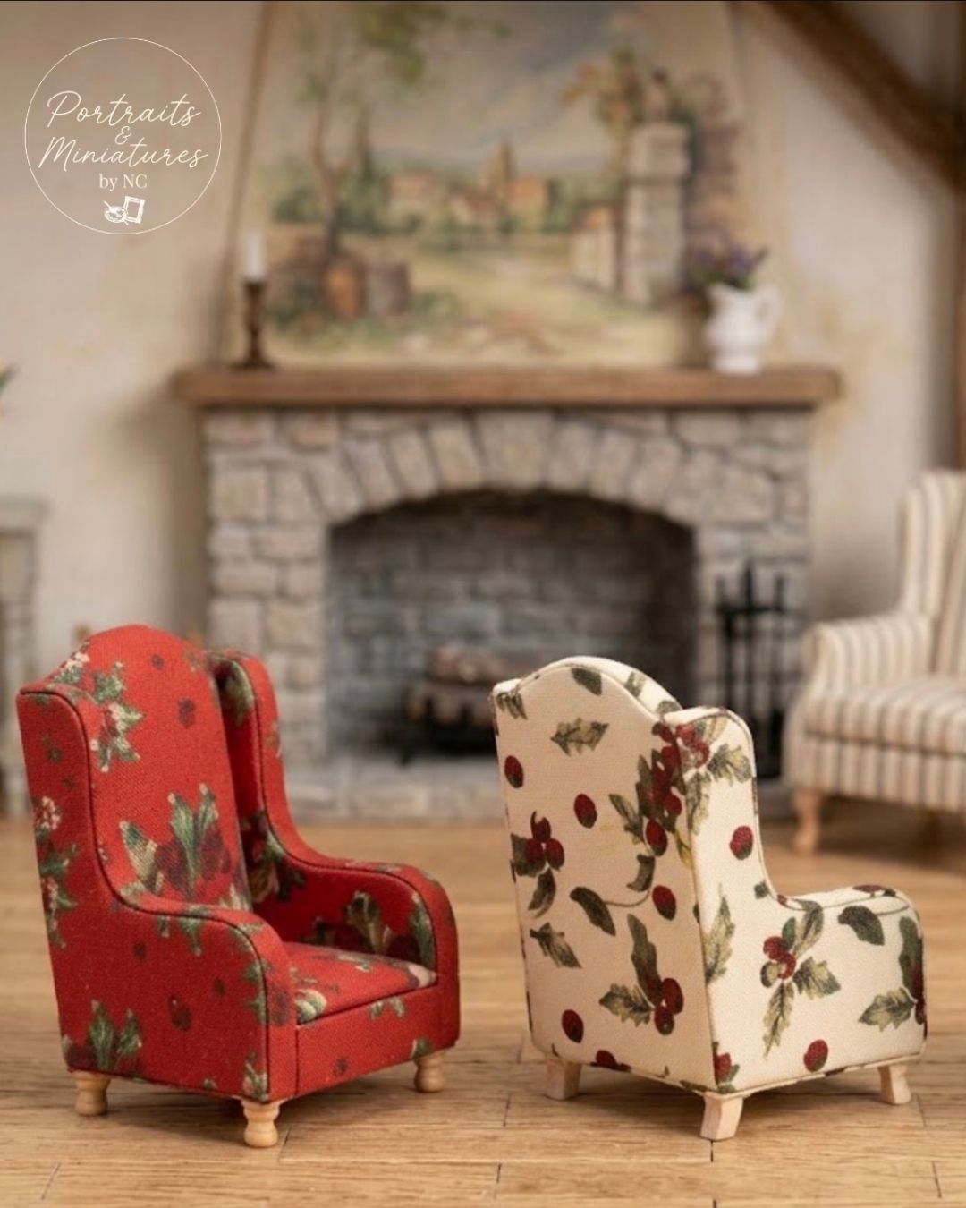 Two miniature wingback armchairs in a dollhouse-style living room setting. The left chair is red with a green holly and berry pattern, and the right chair is cream with a matching berry and holly pattern.