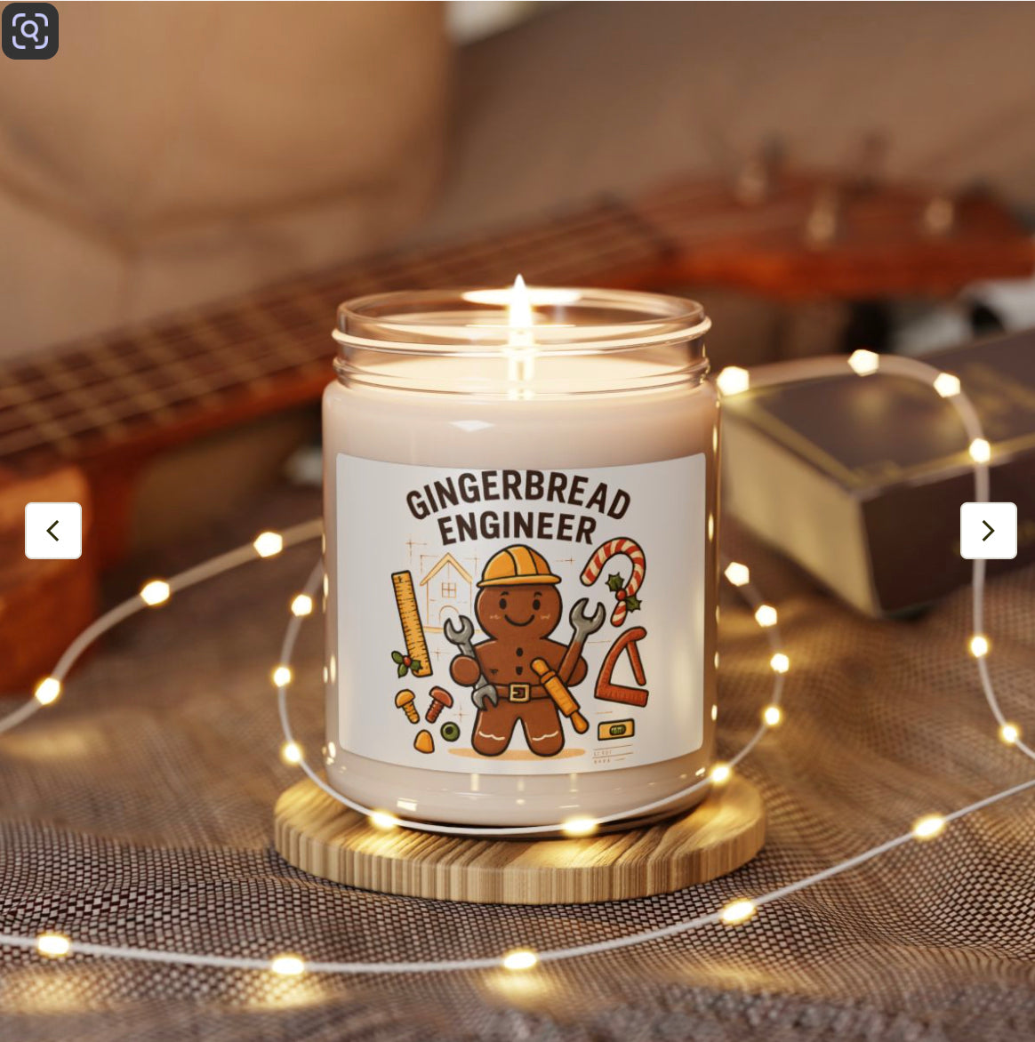 Candle with a gingerbread engineer design on a wooden coaster with string lights and a guitar in the background.