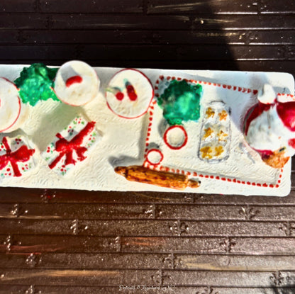 Decorative Christmas-themed candy tray with Santa Claus and presents on a wooden surface.