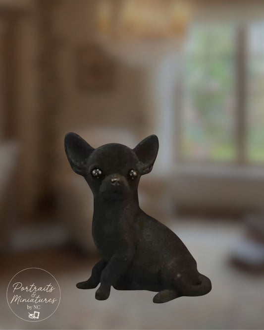A small black Chihuahua dog figurine with large ears and glossy eyes, posed sitting against a softly blurred indoor background. A circular 'Portraits Miniatures by NC watermark appears in the lower left.