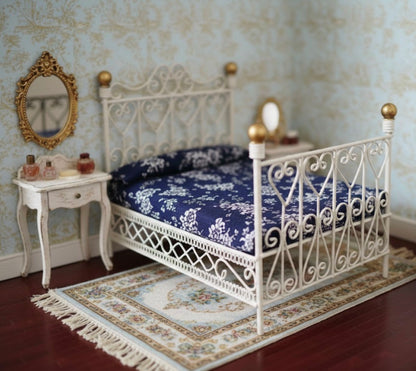 White dollhouse rod iron bed with blue floral bedding in a decorated room.